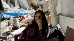 امرأة غزية أمام منزلها المدمّر 