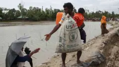 ইউএসএইড লেখা বস্তা হাতে একজন রোহিঙ্গা (ফাইল ছবি)