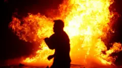 Seorang pria melewati pembakaran pembatas jalan.