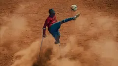 An amputee football player kicks a ball