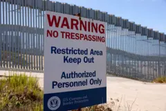 Uma placa da Alfândega e Proteção de Fronteiras dos EUA (CBP) pode ser vista no Parque Estadual Border Field, com o muro da fronteira entre os EUA e o México ao fundo.