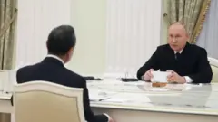 타원형의 테이블에서 회담 중인 푸틴 대통령과 왕이 위원