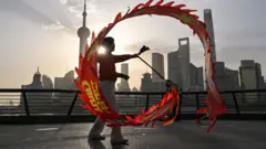 上海外灘黃浦江畔一位女士在朝陽照耀下揮舞甩龍（14/4/2025）