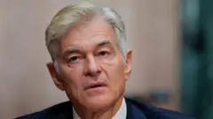 Mehmet Oz, con cabello gris, traje azul marino con camisa blanca y corbata roja, habla por un micrófono durante una audiencia de confirmación en el Capitolio de los Estados Unidos en Washington.