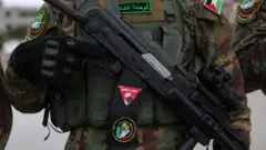 یک فرد با لباس نظامی و تجهیزات اسلحه به دست، چهره او در عکس نیست