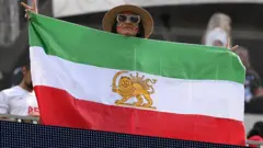 An Iranian fan shows a pre-revolutionary Iranian flag ahead of the 2026 World Cup Group G football match between Iran and New Zealand at Los Angeles Stadium in Inglewood on June 15, 2026.