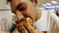 Joven comiendo una hamburguesa.