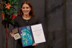 Uma mulher segurando um diploma e uma medalha