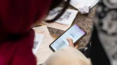 امرأة ترتدي حجاباً أحمر تنظر إلى هاتف يعمل عليه تطبيق الـVPN