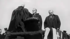 William McKinley toma posse como presidente dos Estados Unidos, na presença de seu antecessor, Grover Cleveland.