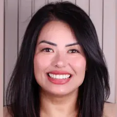 Viviana Makiyama sorrindo para foto, em frente a parede