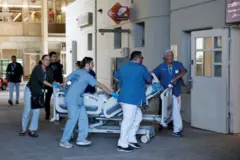 Médicos transportando leito hospitalar na porta de hospital