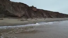 Olas al pie del acantillado sobre el que se sostiene el búnker. El terreno bajo el búnker se aprecia muy erosionado.