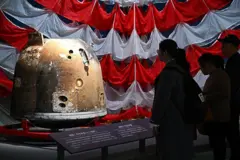 Visitantes observam a cápsula Chang'e 6 em uma exposição.