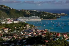Panorámica actual del puerto de Saint Thomas, con pequeñas embarcaciones y un gran crucero sobre un mar azul y un cielo igual de azul.