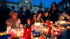 Women light red and white candles at dusk