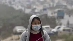 धुम्म परेको मौसममा  मास्क लगाएर हिँडेकी एक किशोरी