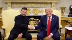 Le président américain Donald J. Trump, à droite, vêtu d'un costume bleu, d'une cravate rouge et d'une chemise blanche, sourit en serrant la main du président ukrainien Volodymyr Zelensky, à gauche, vêtu d'un costume noir, la bouche fermée et l'air aimable, dans le bureau ovale de la Maison Blanche à Washington DC.