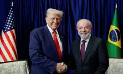 Lula e Trump dando um aperto de mão e sorrindo para a câmera