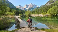Mulher com bicicleta elétrica de montanha nos Alpes Julianos, na Eslovênia, Europa.