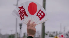 Рука держит веер с японским флагом.