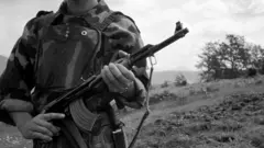A Kosovan soldier holding a gun - black and white photo from June 1999