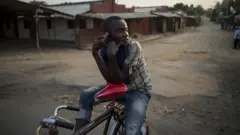 Un jeune homme téléphonant à vélo