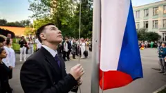 Школьник поднимает российский флаг 