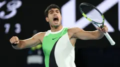 Alcaraz maç sırasında sayı aldıktan sonra seviniyor. Üzerinde yeşil, beyaz ve siyah bir tişört var.