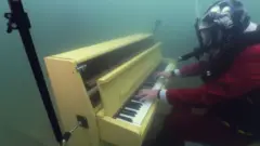 جو جينكينز يعزف على بيانو اصفر تحت الماء