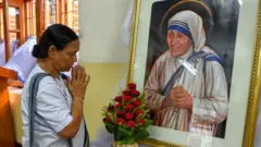 A woman prays in front of a picture of Mother Teresa in India