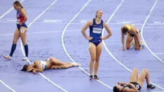 Atletas exaustas deitadas na pista após competir no heptatlo feminino nos Jogos OlímpicosParis 2024 