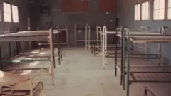 Los barracones en los que jóvenes estudiantes de secundaria vivieron durante seis semanas en Blythe, California, en 1965. La imagen, en la que se ven las literas sin colchones en un espacio con iluminación natural, fue tomada en 1990.