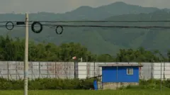A high, metal fence border fence cuts through fields between China and Myanmar in Ruili 