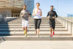 Tres personas bajando unas escaleras en ropa de ejercicio.
