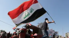 متظاهر يحمل العلم العراقي