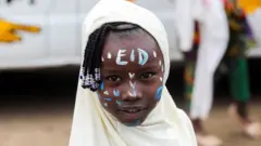 Umwana w'umukobwa ufite ku gahanga ke ijambo 'Eid' ryandikishije irangi.