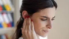 Mujer se cubre un oído.