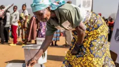 One woman wey tie wrapper and wear blouse dey cast her vote