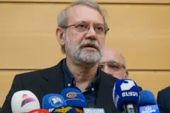 Com jaqueta branca, camisa azul e óculos, o general Ali Larijani fala para um grupo de microfones em um serviço fúnebre, no dia 27 de setembro de 2025