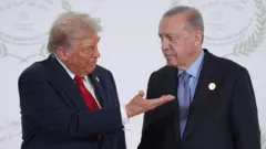 Trump ve Erdoğan yan yanalar. Trump Erdoğan'a eliyle bir yönü işaret ediyor.