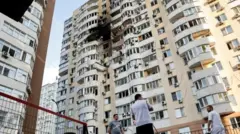 Três homens observam um prédio atingido por um ataque russo em Kiev, na Ucrânia