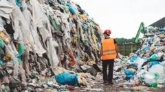 Aterro sanitário com várias roupas jogadas fora.