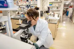 Tamar Gefen em um laboratório olhando algo pelo microscópio