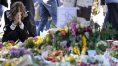 ملکہ کی آخری رسومات سے ایک دن قبل ایک خاتون لندن کے ہائیڈ پارک میں ملکہ کو خراج عقیدت پیش کر رہی ہیں