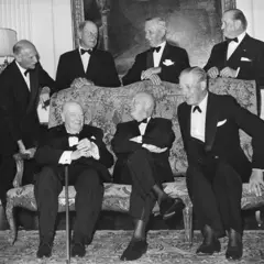 Una fotografía en blanco y negro de hombres con esmoquin, sentados (de izquierda a derecha) están el ex primer ministro británicoWinston Churchill, Eisenhower y el primer ministro Harold MacMillan. De pie (de izquierda a derecha) están el mariscal de campo, vizconde Montgomery; Lord Portal; Arthur Tedder; y el teniente general Sir Frederick Morgan, subjefe del Estado Mayor de Eisenhower durante la guerra.