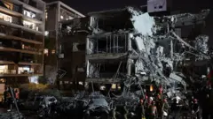 రమత్ గాన్ పట్టణంలో ఇరాన్ దాడిలో ధ్వంసమైన భవనంలో ప్రాణాలతో ఉన్నవారి కోసం గాలిస్తున్నారు 