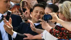 Zelensky takes a photo with a woman in the crowd