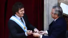 El presidente saliente de Argentina, Alberto Fernández, le entrega el bastón presidencial a Javier Milei 