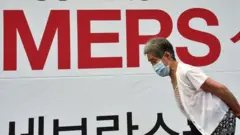 Coreano frente a letrero de MERS
